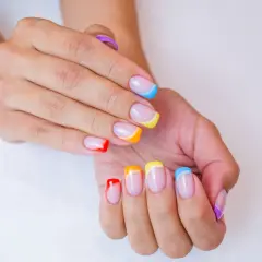 Kolorowe paznokcie na lato: francuski manicure w odcieniach tęczy, od czerwieni po fiolet.