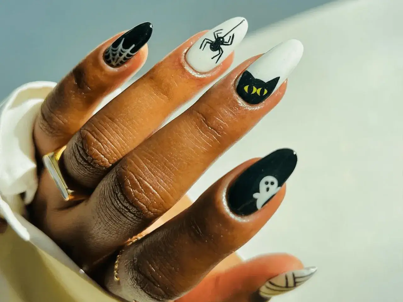 Dłoń z paznokciami halloweenowymi: pajęczyna, pająk, czarny kot i duch. Idealne na Halloween!